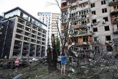 Residents look at damaged buildings following overnight Russian missile and drone strikes, in Kyiv