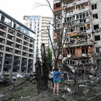 Residents look at damaged buildings following overnight Russian missile and drone strikes, in Kyiv