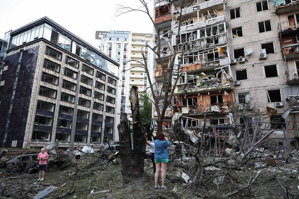 Residents look at damaged buildings following overnight Russian missile and drone strikes, in Kyiv