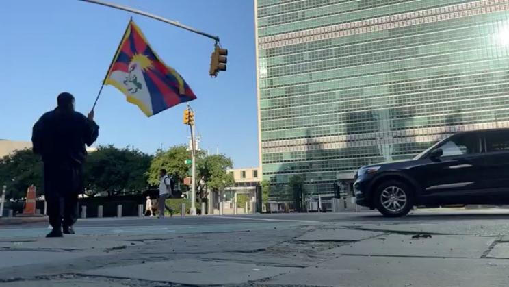 A man identified by Voice of Tibet, a media outlet of exiled Tibetans, as Tibetan activist Lobga Rangzen, walks carrying a Tibetan flag near the United Nations headquarters, before setting himself on fire, in New York