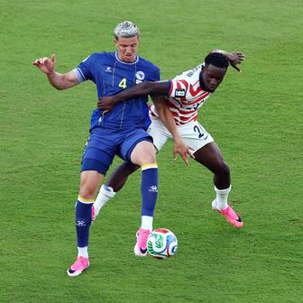 Americký fotbalista Folarin Balogun fauluje Tarika Muhameroviče z Bosny v zápase play off MS 2026.