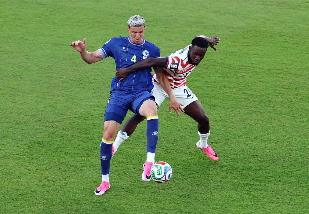 Americký fotbalista Folarin Balogun fauluje Tarika Muhameroviče z Bosny v zápase play off MS 2026.