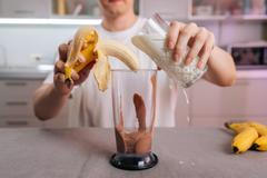 Man,Adding,Milk,And,Peeled,Banana,To,Blender,With,Chocolate