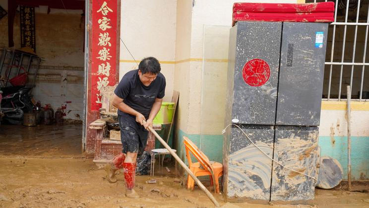 Resident clears mud from a flood-hit home in Hengzhou