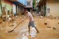 Man clears the mud after heavy rainfall in flooded Sanli town, in Guigang