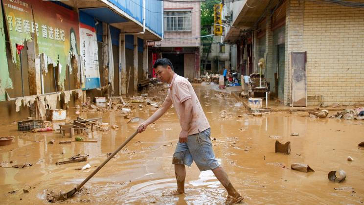 Man clears the mud after heavy rainfall in flooded Sanli town, in Guigang