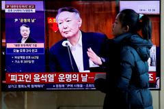 FILE PHOTO: People watch a news report on the sentencing trial of South Korean former president Yoon Suk Yeol's insurrection case in Seoul
