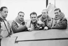 Skupina pilotů polské 303. stíhací perutě RAF stojí u výškového kormidla jednoho ze svých letounů Hawker Hurricane Mk. I na základně Northolt v Middlesexu. Zleva doprava: poručík Mirosław Ferić, nadporučík Bogdan Grzeszczak, poručík Jan Zumbach, nadporučík Zdzisław Henneberg a kapitán John Kent, který v té době velel letce „A“ této perutě.