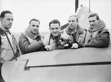Skupina pilotů polské 303. stíhací perutě RAF stojí u výškového kormidla jednoho ze svých letounů Hawker Hurricane Mk. I na základně Northolt v Middlesexu. Zleva doprava: poručík Mirosław Ferić, nadporučík Bogdan Grzeszczak, poručík Jan Zumbach, nadporučík Zdzisław Henneberg a kapitán John Kent, který v té době velel letce „A“ této perutě.