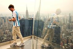 A person takes pictures as the New York City skyline and the Empire State Building are seen from the Edge observation deck through a cover of wildfire smoke in New York
