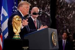 Donald Trump a Gianni Infantino stojí vedle trofeje pro mistry světa ve fotbale během recepce FIFA v newyorské Trump Tower