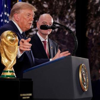 Donald Trump a Gianni Infantino stojí vedle trofeje pro mistry světa ve fotbale během recepce FIFA v newyorské Trump Tower