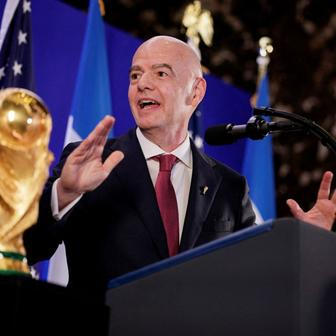 Gianni Infantino stojí vedle trofeje pro mistry světa ve fotbale během recepce FIFA v newyorské Trump Tower
