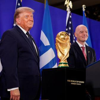 Donald Trump a Gianni Infantino stojí vedle trofeje pro mistry světa ve fotbale během recepce FIFA v newyorské Trump Tower
