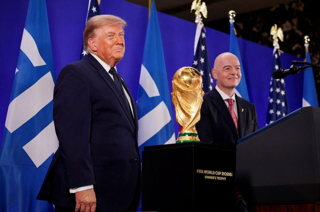 Donald Trump a Gianni Infantino stojí vedle trofeje pro mistry světa ve fotbale během recepce FIFA v newyorské Trump Tower