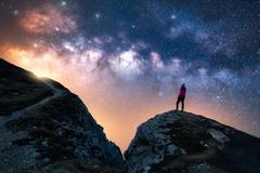 Glowing,Milky,Way,And,Woman,On,Mountain,Peak,At,Starry