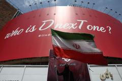 A woman holds an Iranian flag next to a billboard threatening U.S. President Donald Trump is displayed on a building in Tehran
