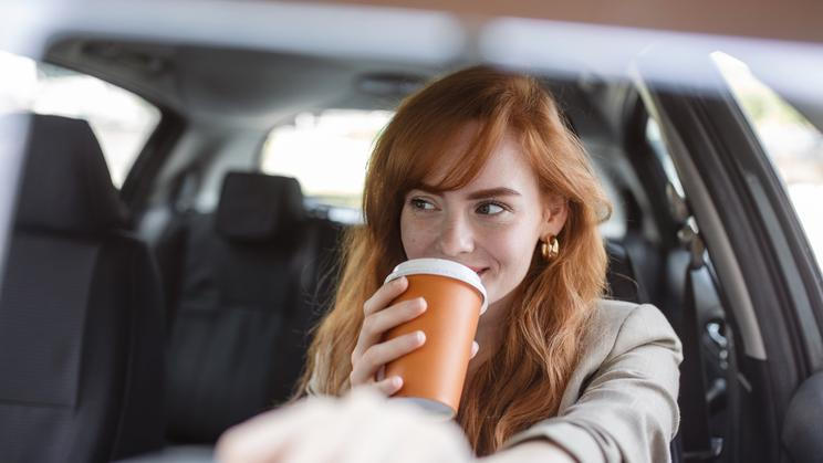 Happy,Young,Woman,With,Coffee,To,Go,Driving,Her,Car.