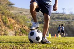 Outdoors, playing soccer on field, multiracial boys practicing with ball and cones