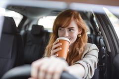 Happy,Young,Woman,With,Coffee,To,Go,Driving,Her,Car.