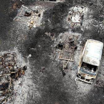 A drone view shows a burnt vehicle in an area affected by wildfire, in Le Porge