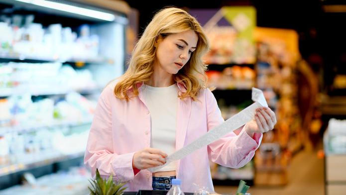 Woman,Holding,A,Long,Shopping,Receipt,In,A,Supermarket,,Checking