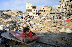 A Palestinian girl child lies on a damaged mattress at the site of Wednesday's Israeli strike on a house whose residents were pre-warned by the Israeli military to evacuate, in Gaza City