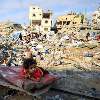A Palestinian girl child lies on a damaged mattress at the site of Wednesday's Israeli strike on a house whose residents were pre-warned by the Israeli military to evacuate, in Gaza City