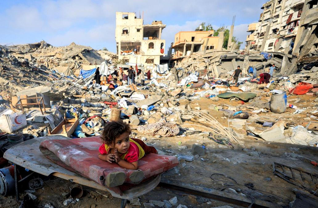 A Palestinian girl child lies on a damaged mattress at the site of Wednesday's Israeli strike on a house whose residents were pre-warned by the Israeli military to evacuate, in Gaza City