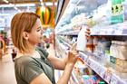 Young,Woman,Buyer,Chooses,Milk,In,Bottle,In,Grocery,Store