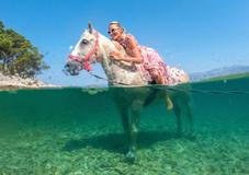 A woman poses on a horse named 'Perlaz' after swimming with it during the heatwave in Supetar on the island of Brac