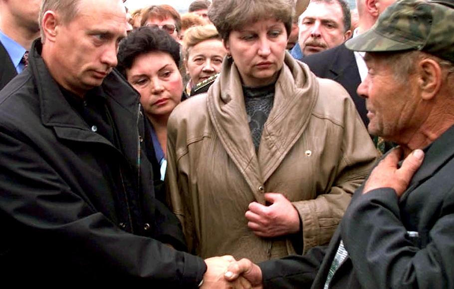 Vidjajevo, Rusko, 22. srpna 2000 – Ruský prezident Vladimir Putin (vlevo) při setkání s rodinami námořníků z ponorky Kursk podává ruku jednomu z příbuzných. Uprostřed přihlíží Irina Ljachinová, manželka velitele ponorky.