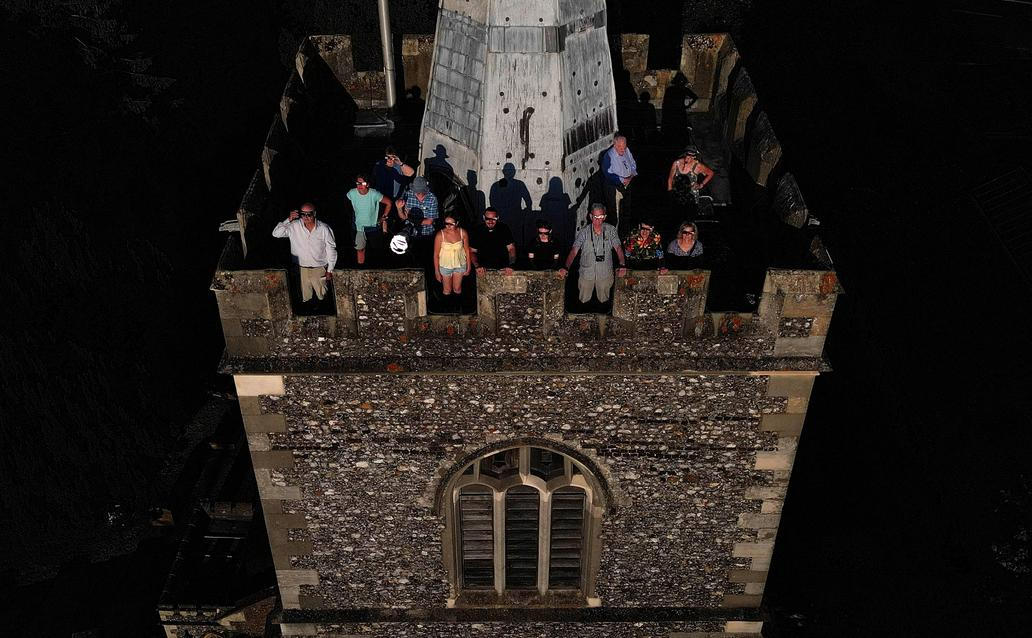 People wear special protective glasses to observe a partial solar eclipse at the top of St Mary’s Church bell tower in Rickmansworth