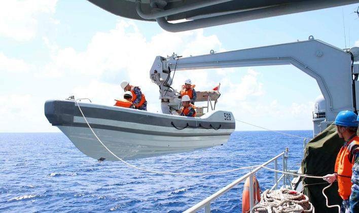 A search boat carrying rescue workers is set down from Mianyang warship on the waters suspected to be the site of the missing Beijing-bound Malaysia Airlines flight MH370