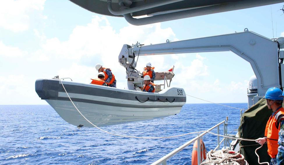 A search boat carrying rescue workers is set down from Mianyang warship on the waters suspected to be the site of the missing Beijing-bound Malaysia Airlines flight MH370