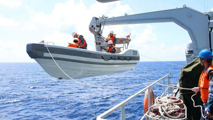 A search boat carrying rescue workers is set down from Mianyang warship on the waters suspected to be the site of the missing Beijing-bound Malaysia Airlines flight MH370