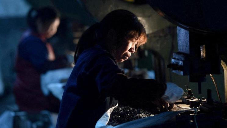 FILE PHOTO: Employees work on a production line manufacturing metal parts for furniture at a factory in Hangzhou