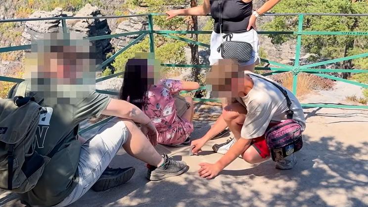 Snímek zachycuje návštěvníka, který ryje do skály.