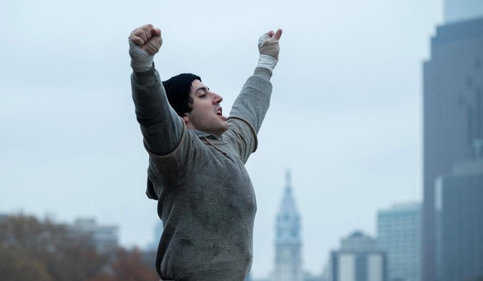 Anthony Ippolito jako herec Sylvester Stallone ve filmu Já, Rocky (2026). Vítězné gesto s rukama nad hlavou se stalo ikonickým.