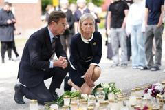 Švédský premiér Ulf Kristersson a opoziční lídryně Magdalena Anderssonová u pietního místa před školou ve Fagerstě den po útoku, 22. srpna 2026.