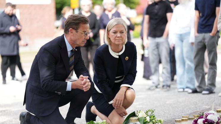 Švédský premiér Ulf Kristersson a opoziční lídryně Magdalena Anderssonová u pietního místa před školou ve Fagerstě den po útoku, 22. srpna 2026.