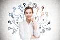 Cheerful,Young,Businesswoman,Standing,Near,Concrete,Wall,With,Question,Marks