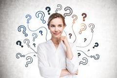 Cheerful,Young,Businesswoman,Standing,Near,Concrete,Wall,With,Question,Marks