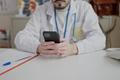 Young,Hispanic,Man,Doctor,Using,Smartphone,Working,At,Clinic