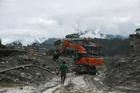 An excavator clears a muddy path after flash floods and a mudslide in Trishuli
