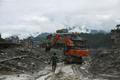 An excavator clears a muddy path after flash floods and a mudslide in Trishuli