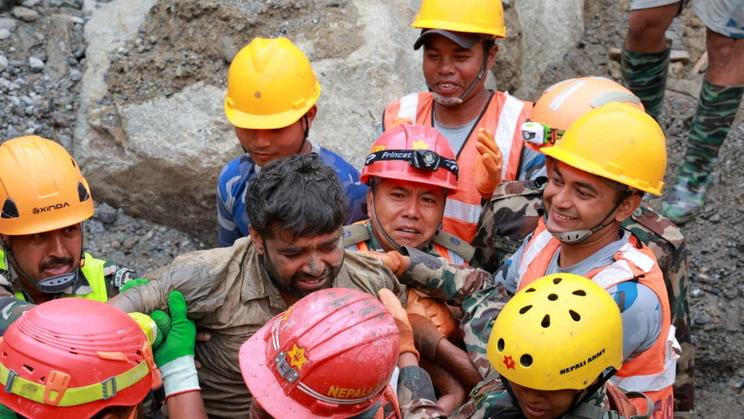 Survivor Sanjay Sah carried by members of a search and rescue team after they rescued alive two people who had been trapped inside a tunnel at the Upper Trishuli-3A Hydropower Project