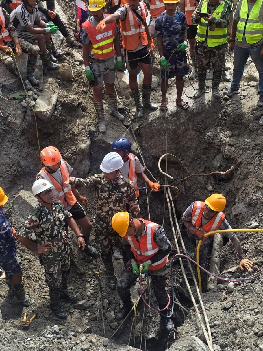 Members of a search and rescue team work to remove the body of a person who was trapped inside a tunnel at the Upper Trishuli-3A Hydropower Project