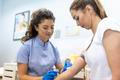 ["Medical technologist doing a blood draw services for patient. lab assistant with sterile rubber gloves taking blood sample from patient."]