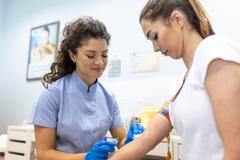 ["Medical technologist doing a blood draw services for patient. lab assistant with sterile rubber gloves taking blood sample from patient."]